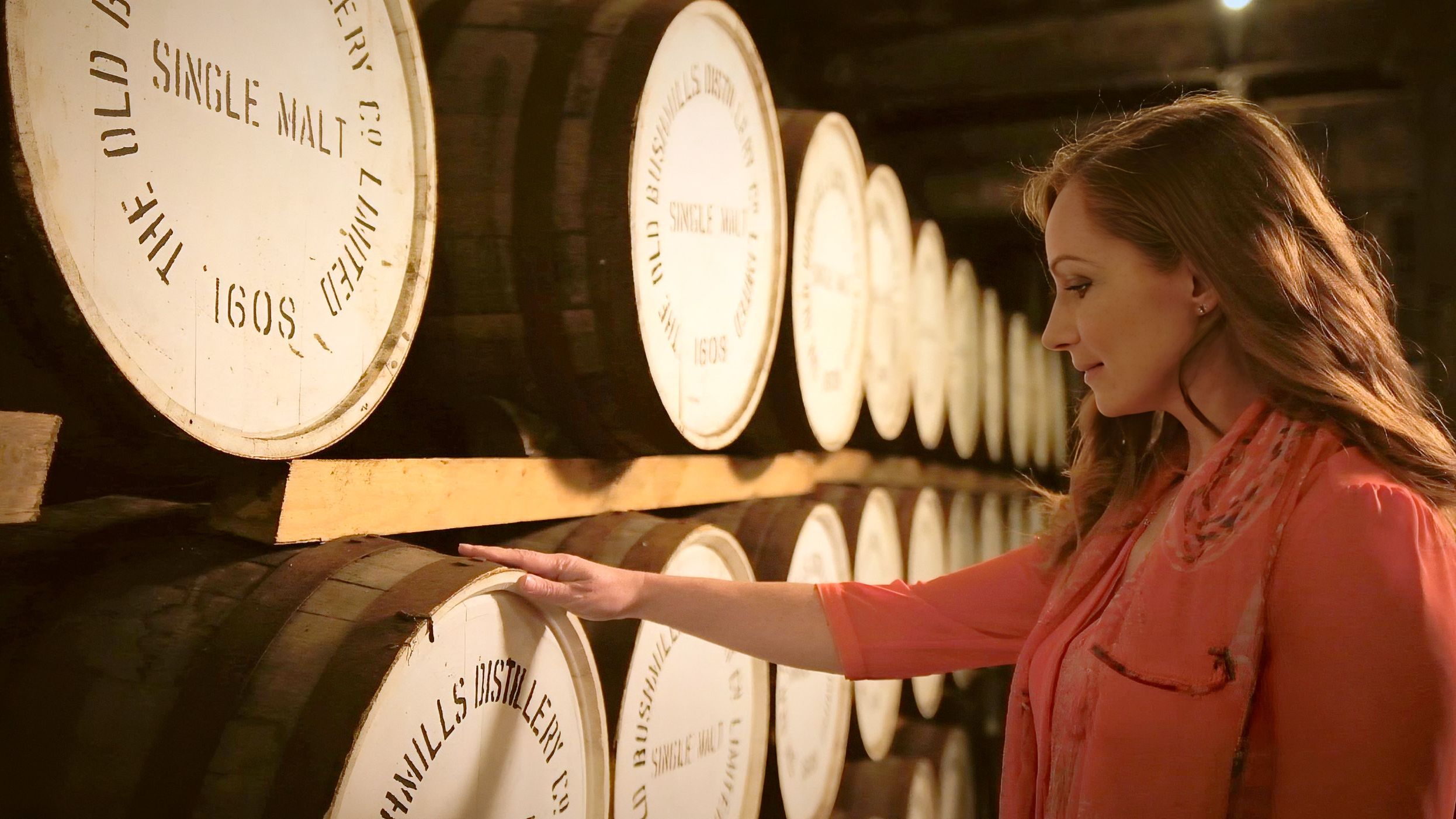 Woman touching whiskey casks in Bushmills during a Tourism Northern Ireland shoot